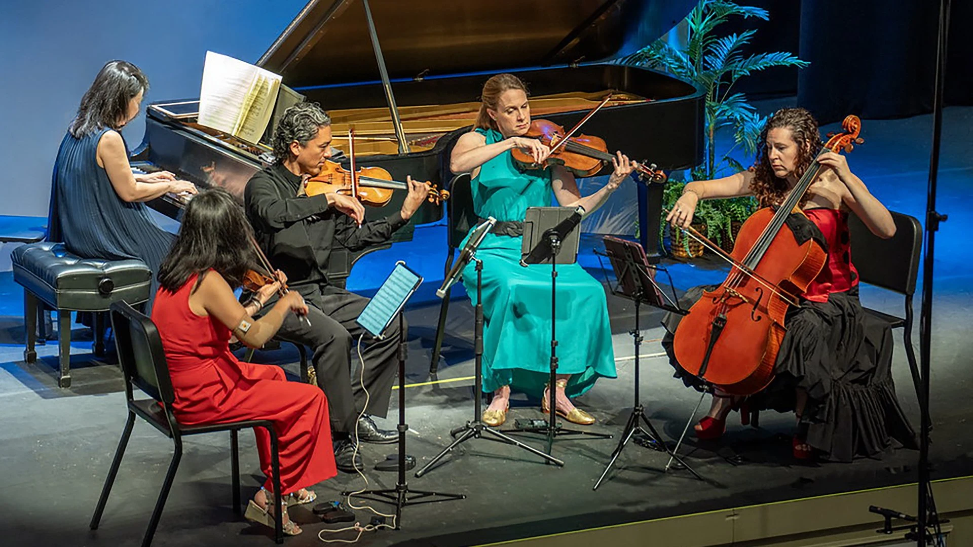 A pianist and four string players performing together on stage